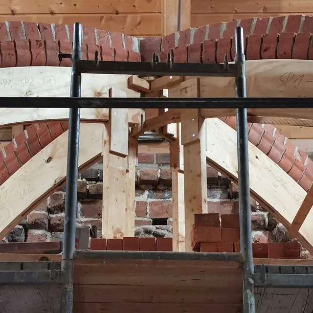 Ein neu gemauerter Backsteinbogen, gestützt von einem Holzrahmen.