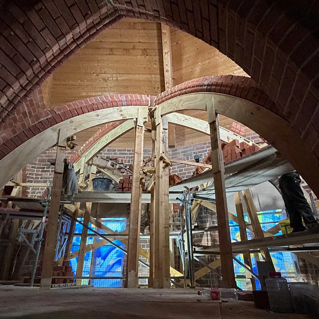 Ein neuer Backsteinbogen für das Kirchengewölbe wird mit einer Holzform gemauert.