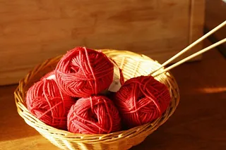 Ein Korb mit roter Wolle und Stricknadeln, für eine Handarbeitsgruppe.