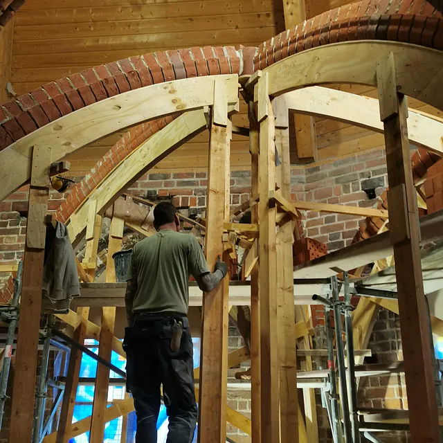 Ein Arbeiter baut die Holzkonstruktion für ein Kirchengewölbe.