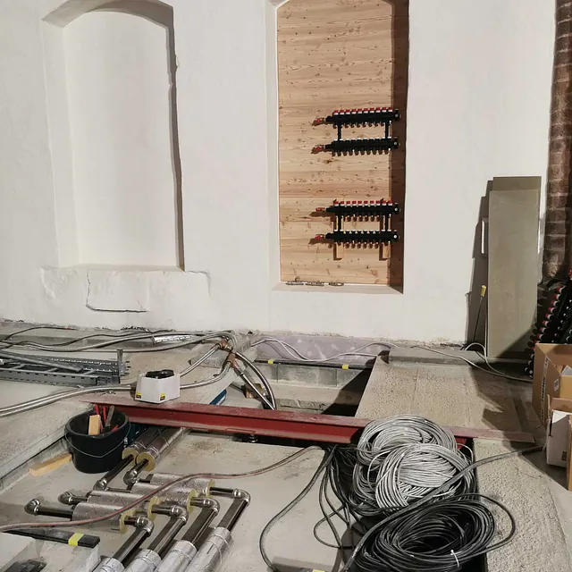 Kircheninneres in Renovierung, mit offenem Boden und Weinregalen in der Wand.