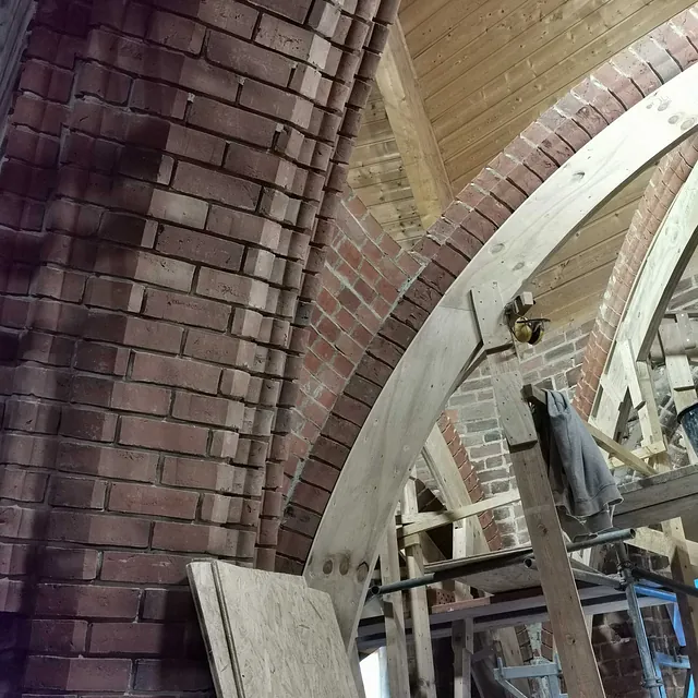 Ein neuer Backsteinbogen wird gemauert und mit einer alten Säule verbunden.